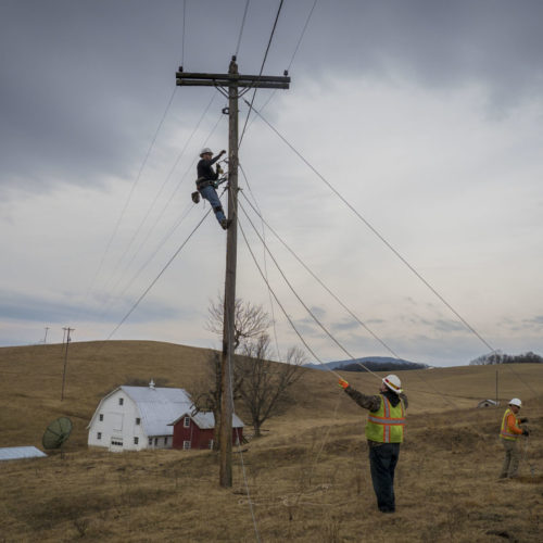 communications workers with telephone pole in rural field