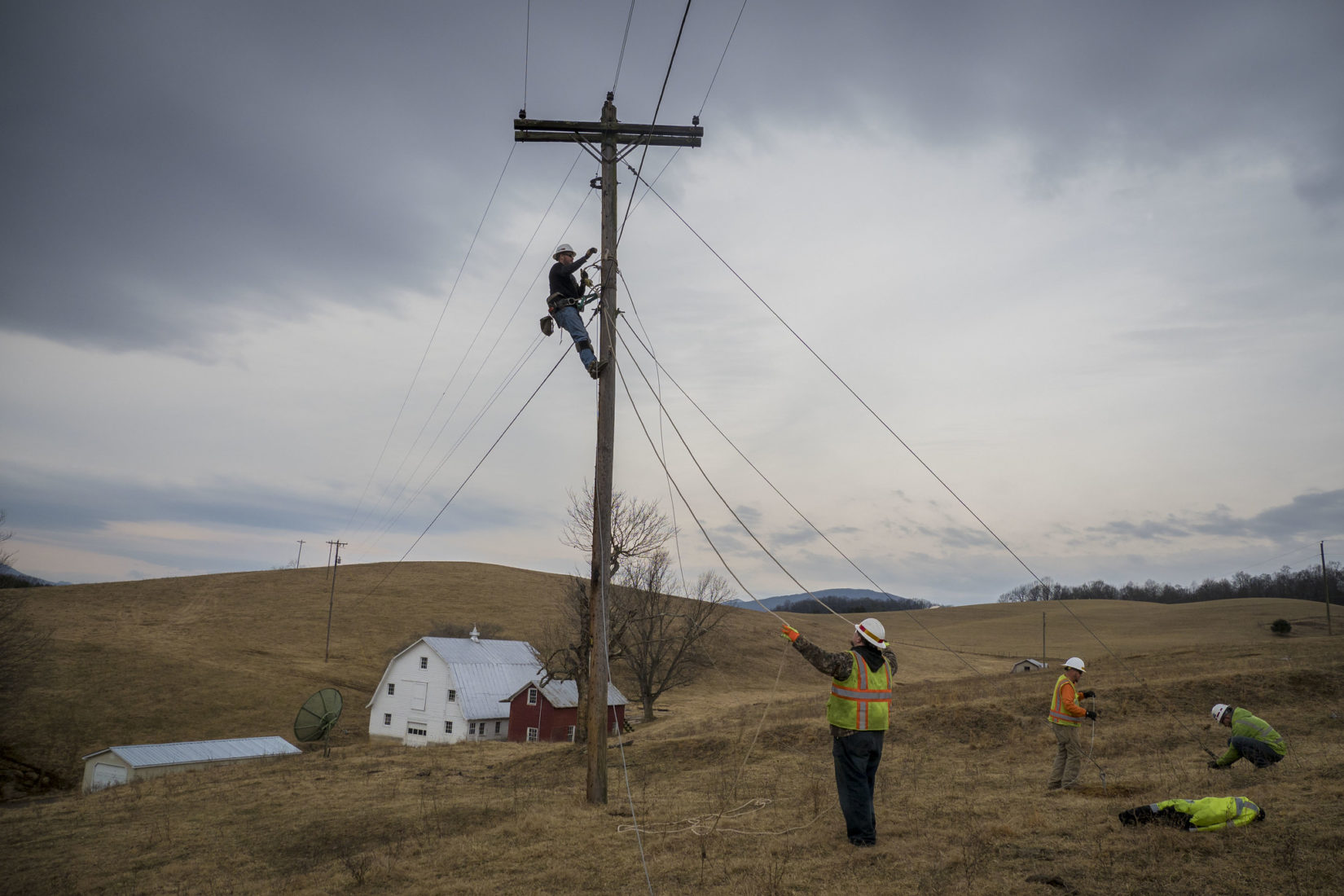communications workers with telephone pole in rural field