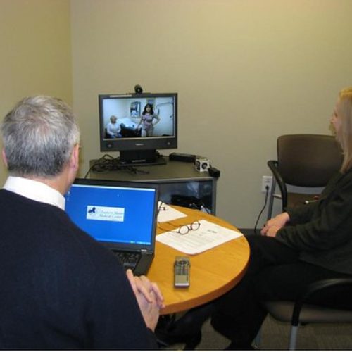 man and woman speaking to doctor via computer link