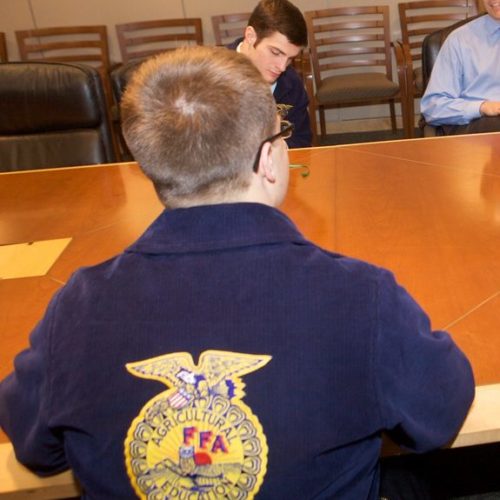 youth in blue FFA jacket at table