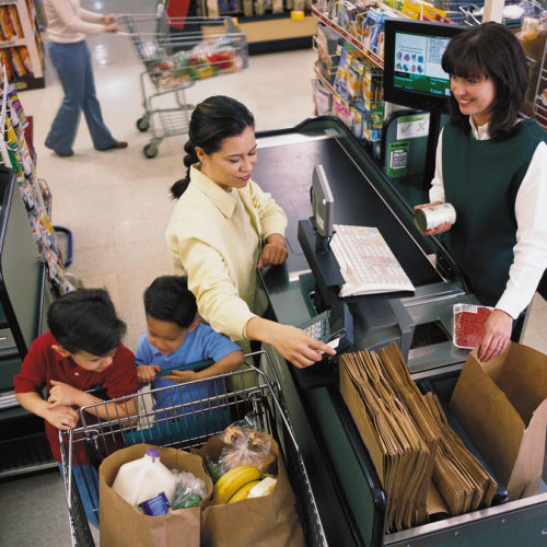 woman with two children and shopping cart at grocery store checkout