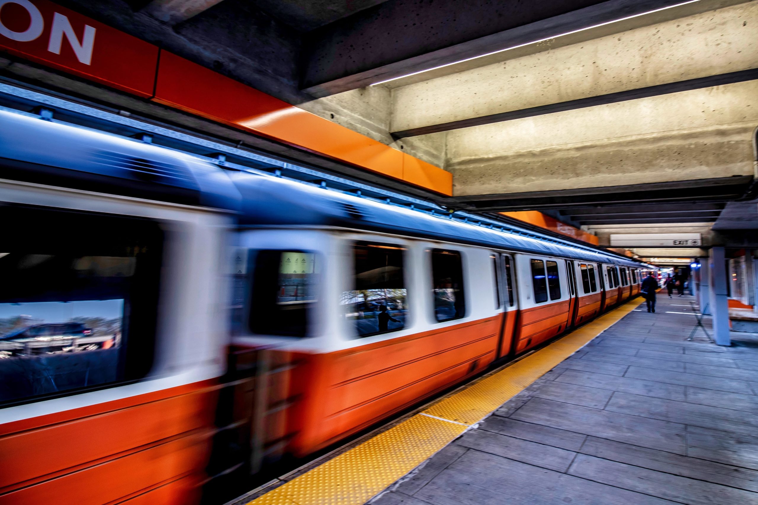 orange and white subway train going through a station