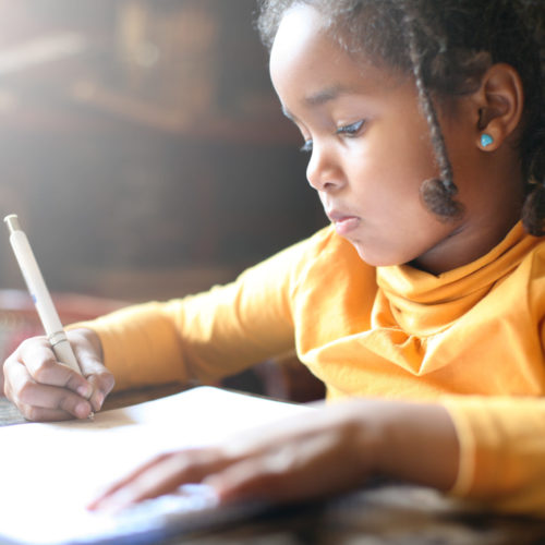 African American girl with yellow shirt writing