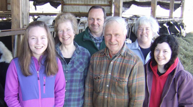 Family members on a farm with cows in background