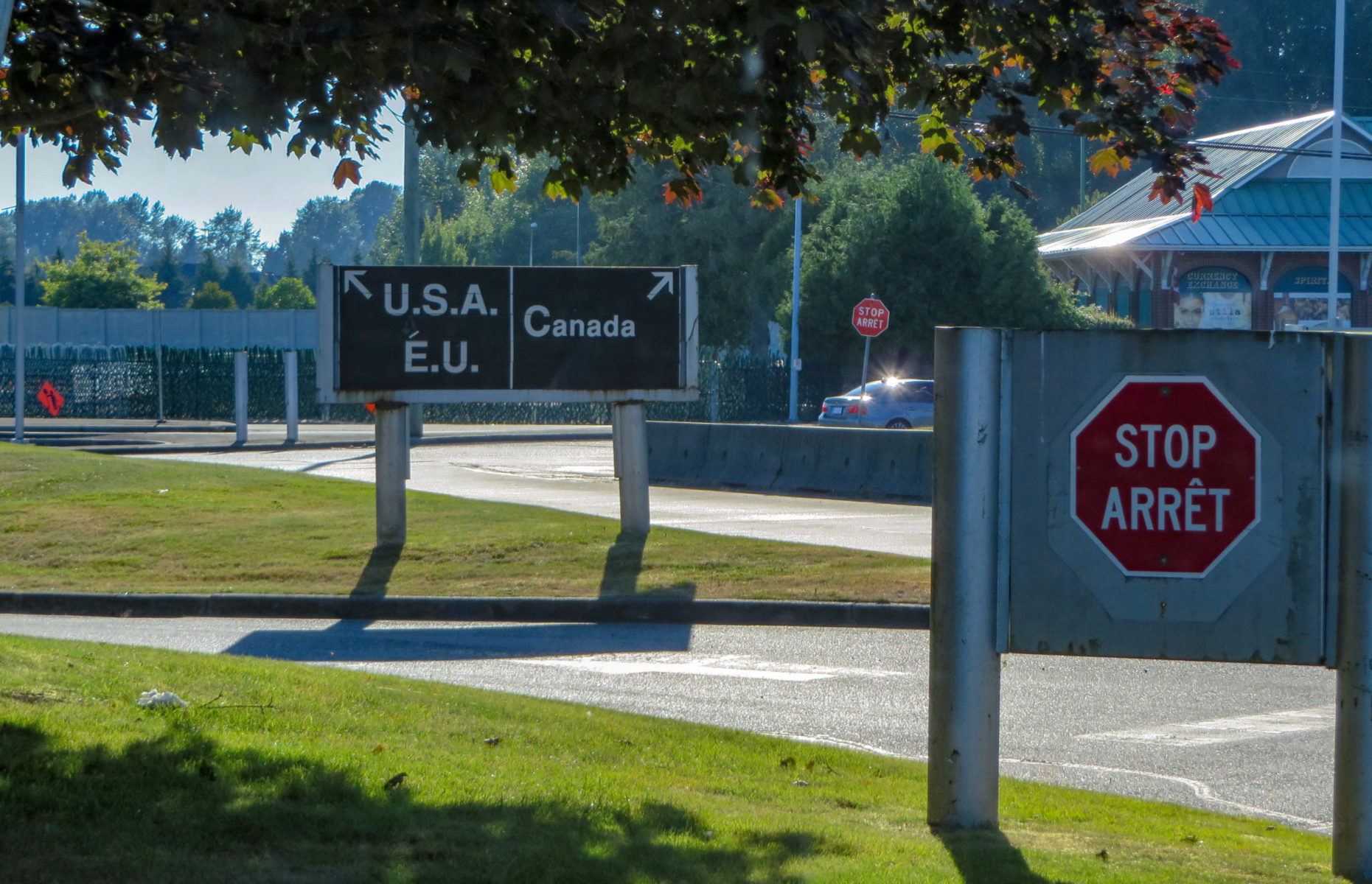two signs under trees at border
