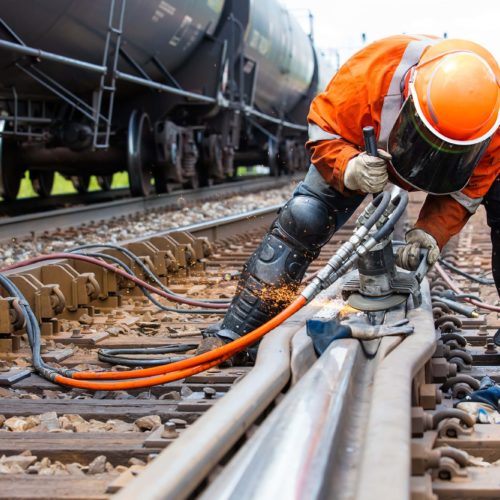 rail worker with orange vest and welding equipment