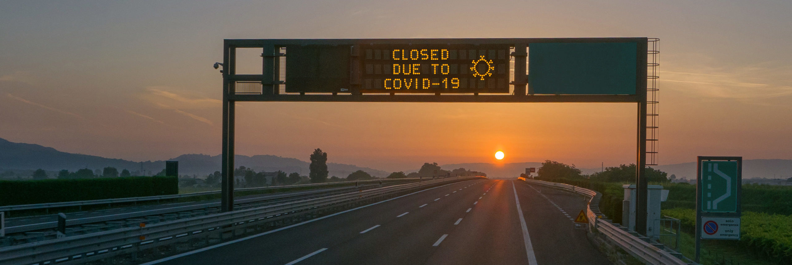 overhead road sign on highway at sunset